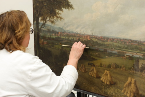A conservator at work on the painting of Preston from Penwortham Hill by John Jenkinson