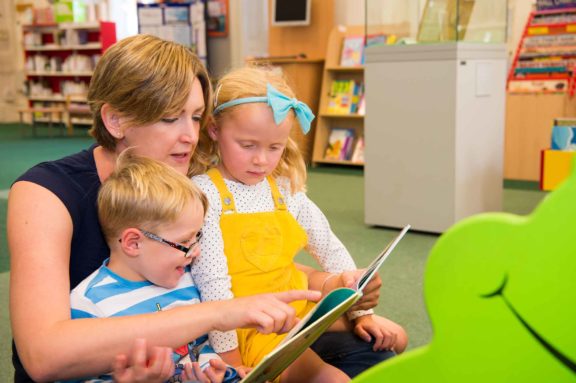 Children and their mother enjoy books in the Harris library