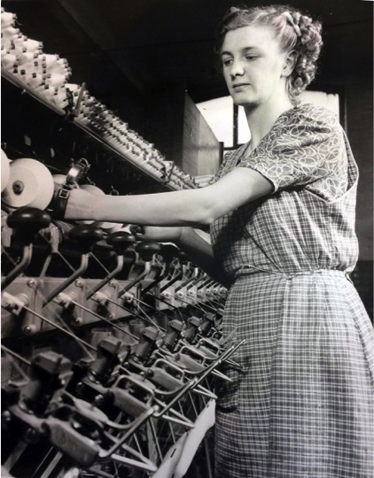 Lady working in cotton factory, operating cotton reel machine.