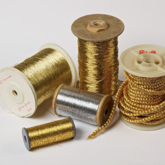 5 cotton reels with golden thread on them.