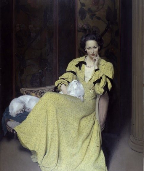 Lady sat in chair looking seductively in armchair with two small fluffy dogs. Lady is wearing long satin yellow dress.