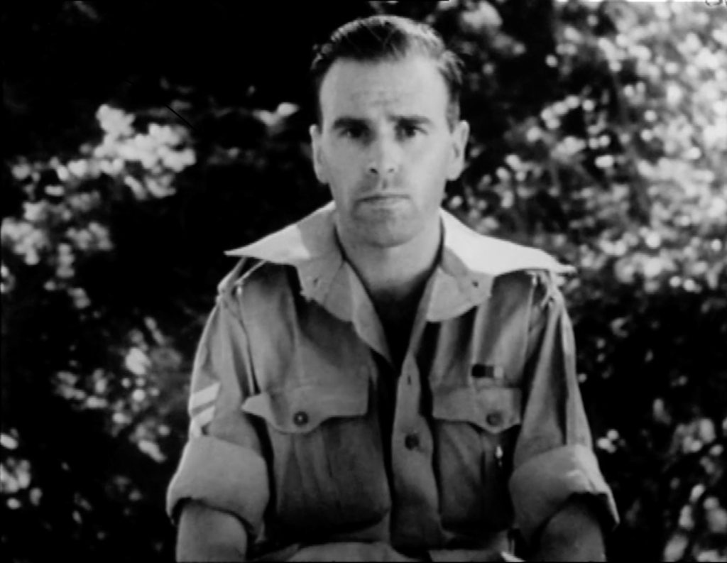 Man in army uniform speaking directly to camera. Black and white camera footage that links to full video once you click on it