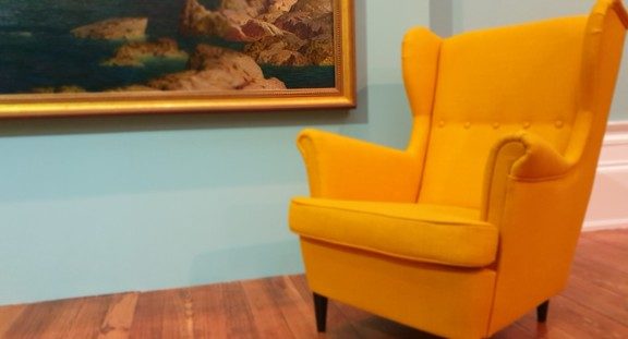 Yellow chair next to serene painting