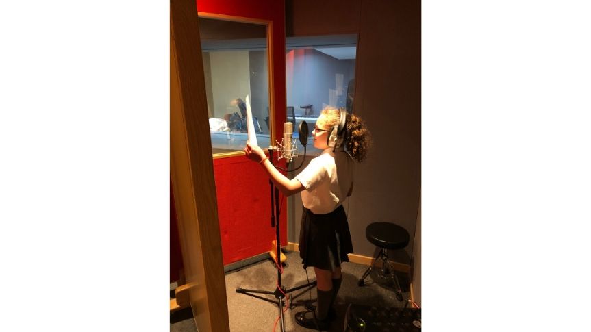 Second Primary school aged girl recording voice over in studio with head phones on.