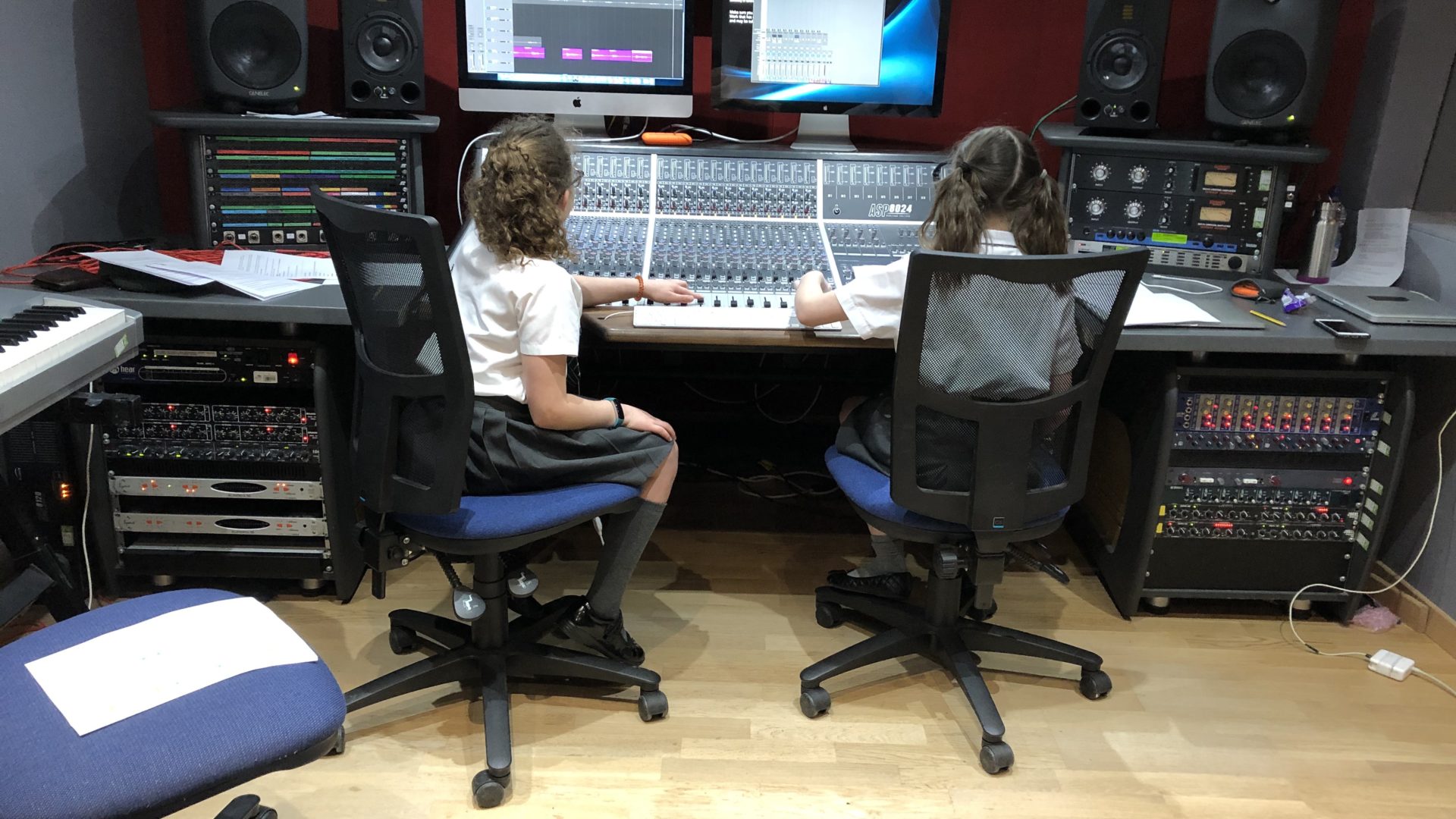 two girls sat at sound desk in recording studio