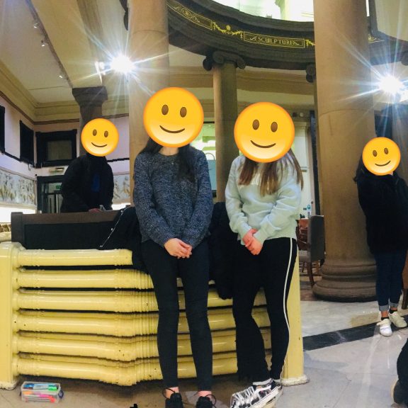 Group of young people stood in Harris Cafe - all of their faces are covered with a smiley face emoji.