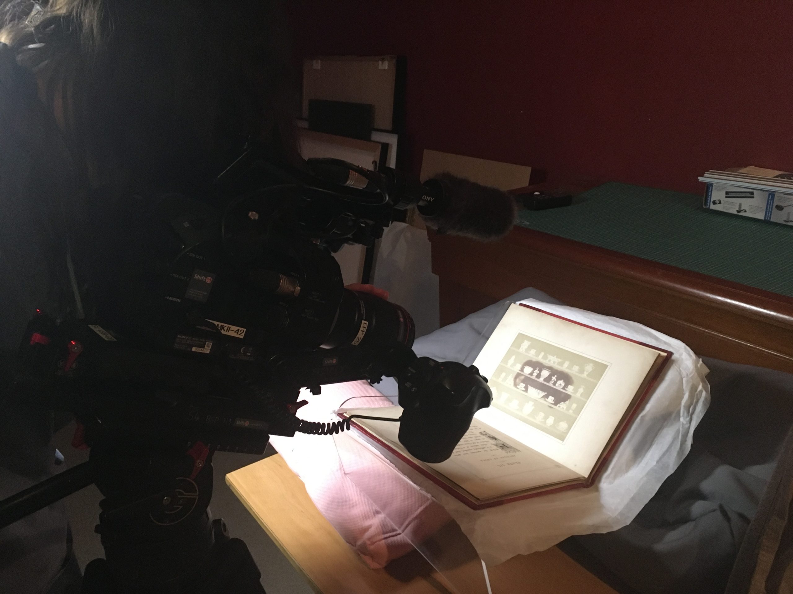 Special collection book being filmed by videographer in dark room.