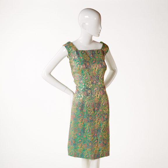 Image shows a mannequin wearing a shift style evening dress woven with stylised green, pink, purple and gold floral motifs.