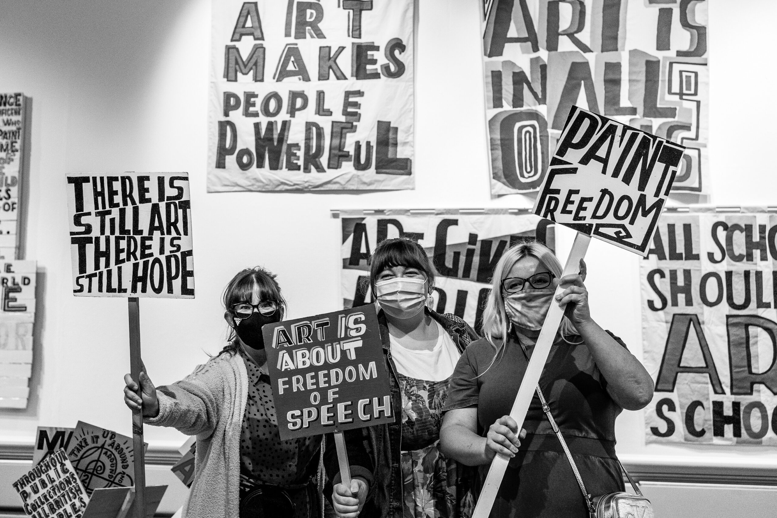 People in the art gallery with placards with messages on from the exhibition