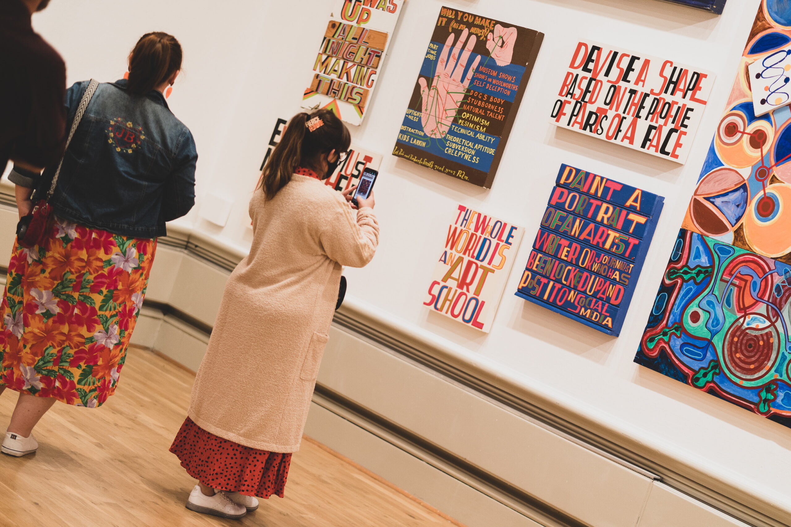 A person looking at colourful art works on a gallery wall