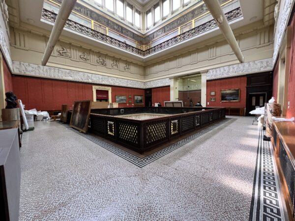 An image showing the second floor of the Harris with paintings removed from the walls and leaning against a railing ready for conservation and moving