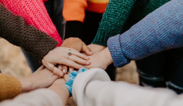 Community image with seven hands stacked together in the middle