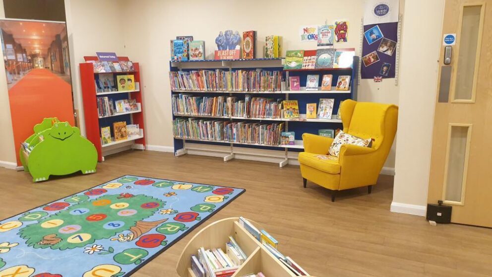 Image of the Harris children's library with a mustard yellow chair in front of bookcases