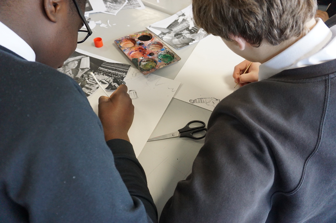 Image of two students from a local school creating a collage in the planning stages of 'the links in the chain are of equal strength