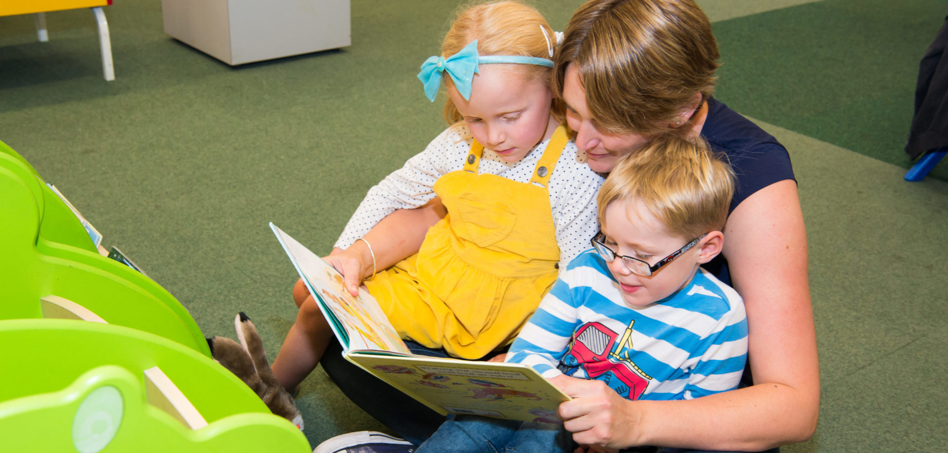 An image of two children reading with their Mother