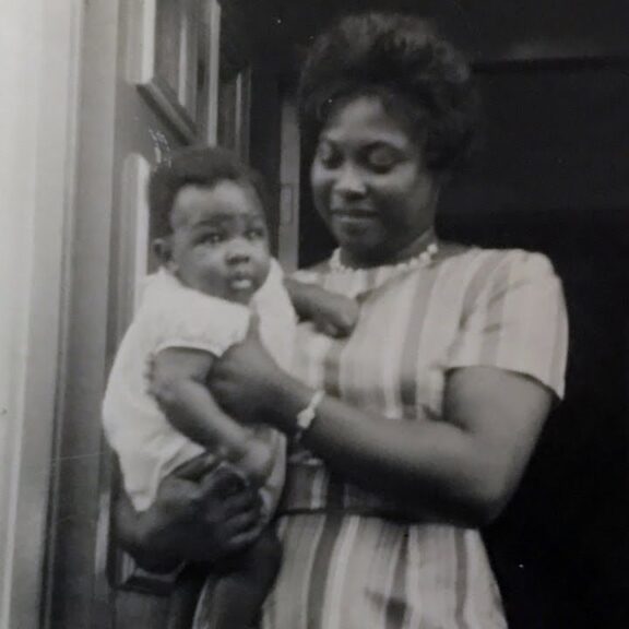 Image of Maxine Grant in a doorway holding a baby
