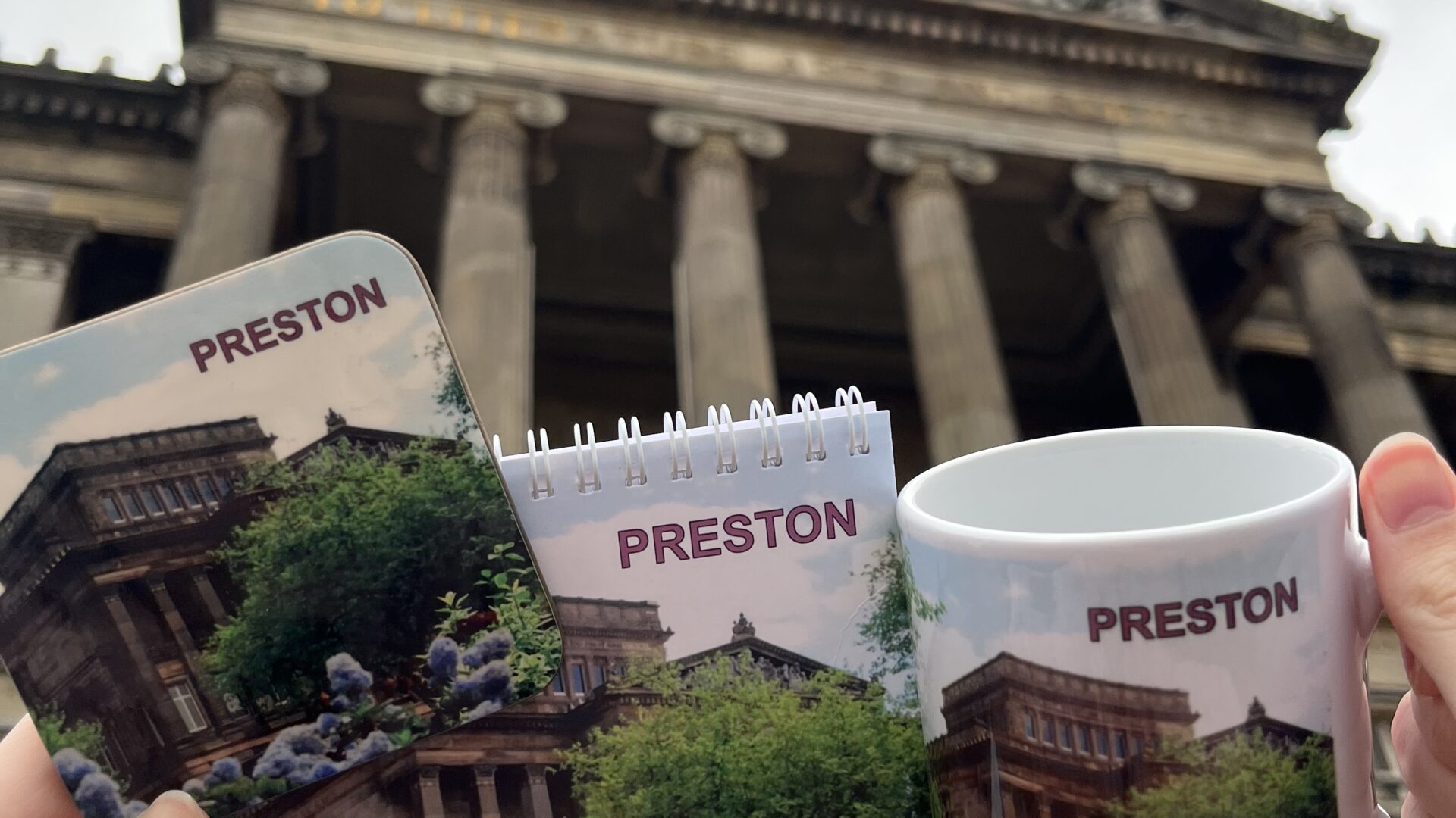 Image taken outside the Harris with Preston merchandise in the form of a mug, notepad and coaster.