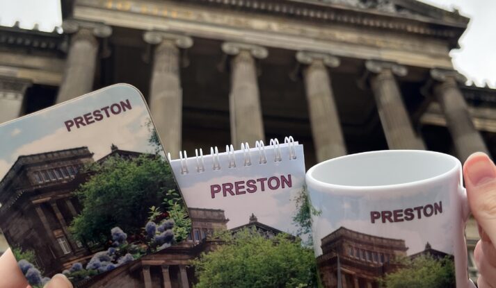 Image taken outside the Harris with Preston merchandise in the form of a mug, notepad and coaster.