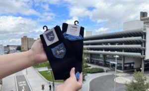 A pair of Preston Socks held up in front of Preston Bus station