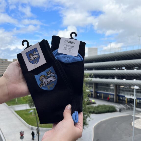 A pair of Preston Socks held up in front of Preston Bus station