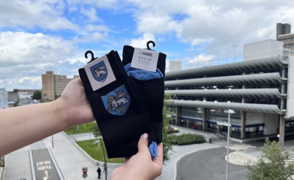 A pair of Preston Socks held up in front of Preston Bus station