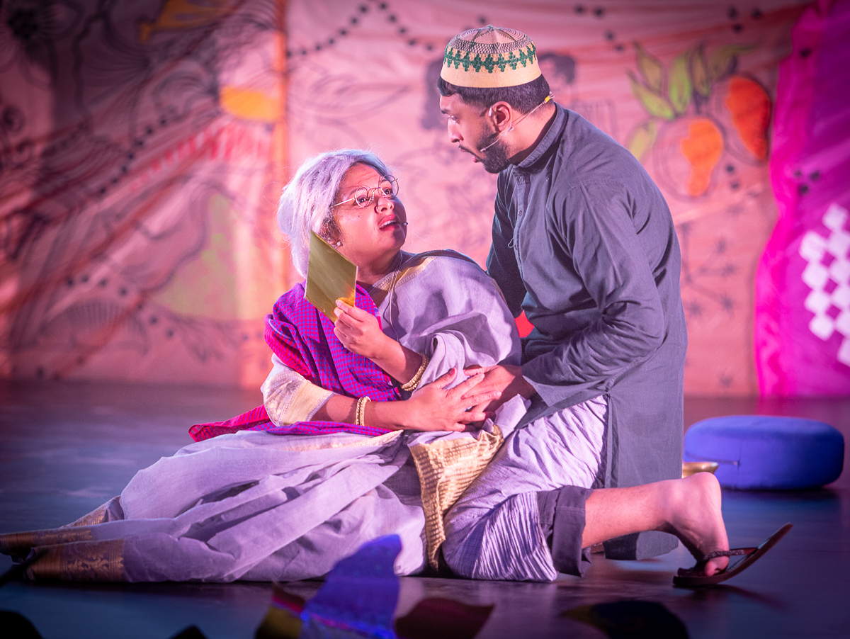 Image of two performers acting against a brightly coloured backdrop.