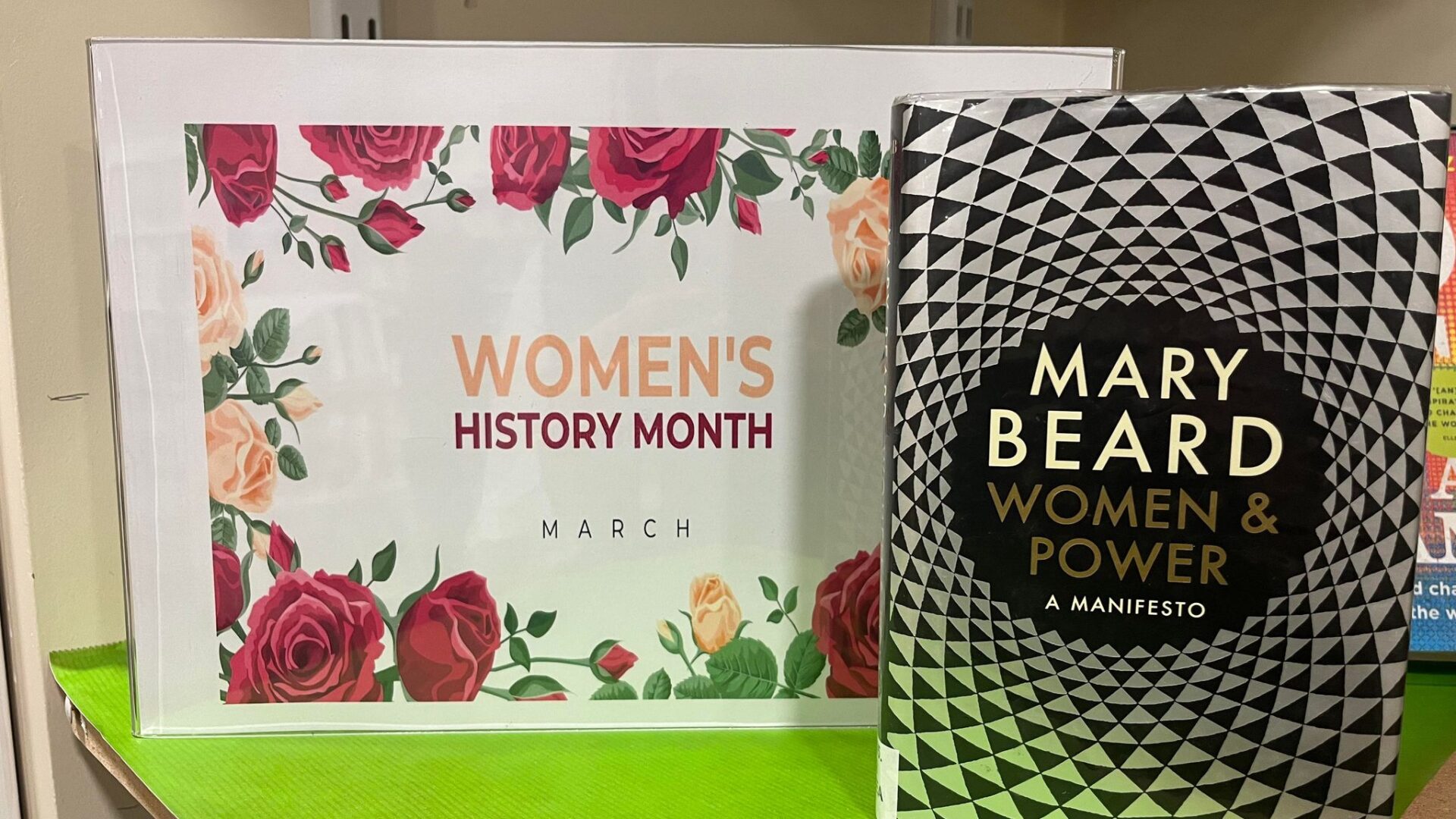 Image of a book next to a womens history month poster