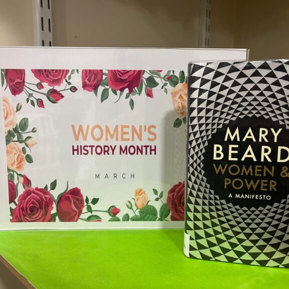 Image of a book next to a womens history month poster