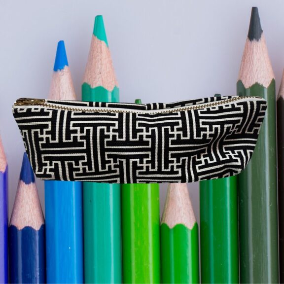 A black and white pencil case with coloured pencils in the background.