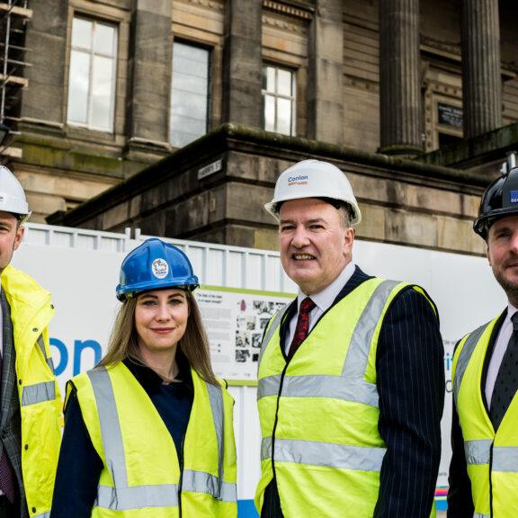 Image of four people in hi-vis and branded helmets.