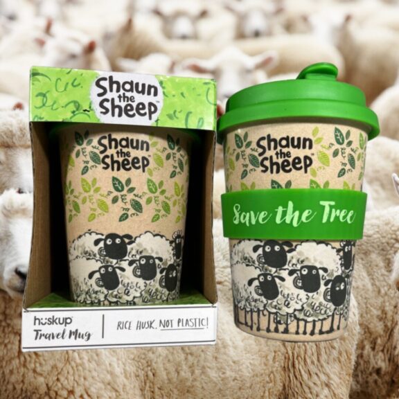 A husk travel cup with sheep in the background.