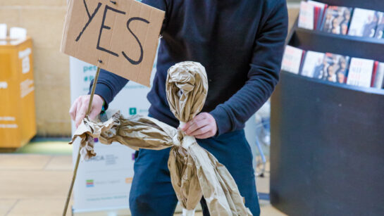 Man in a cap holding a paper puppet