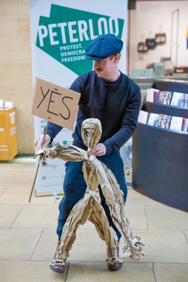 Man in a cap holding a paper puppet