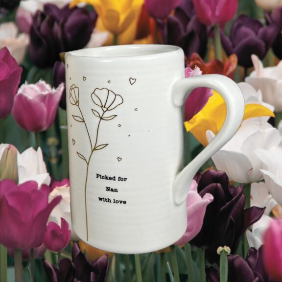 A ceramic jug with tulips in the background.