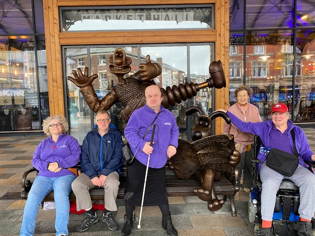 An image of a group of people surrounding the Wallace and Gromit statue at Preston Markets.