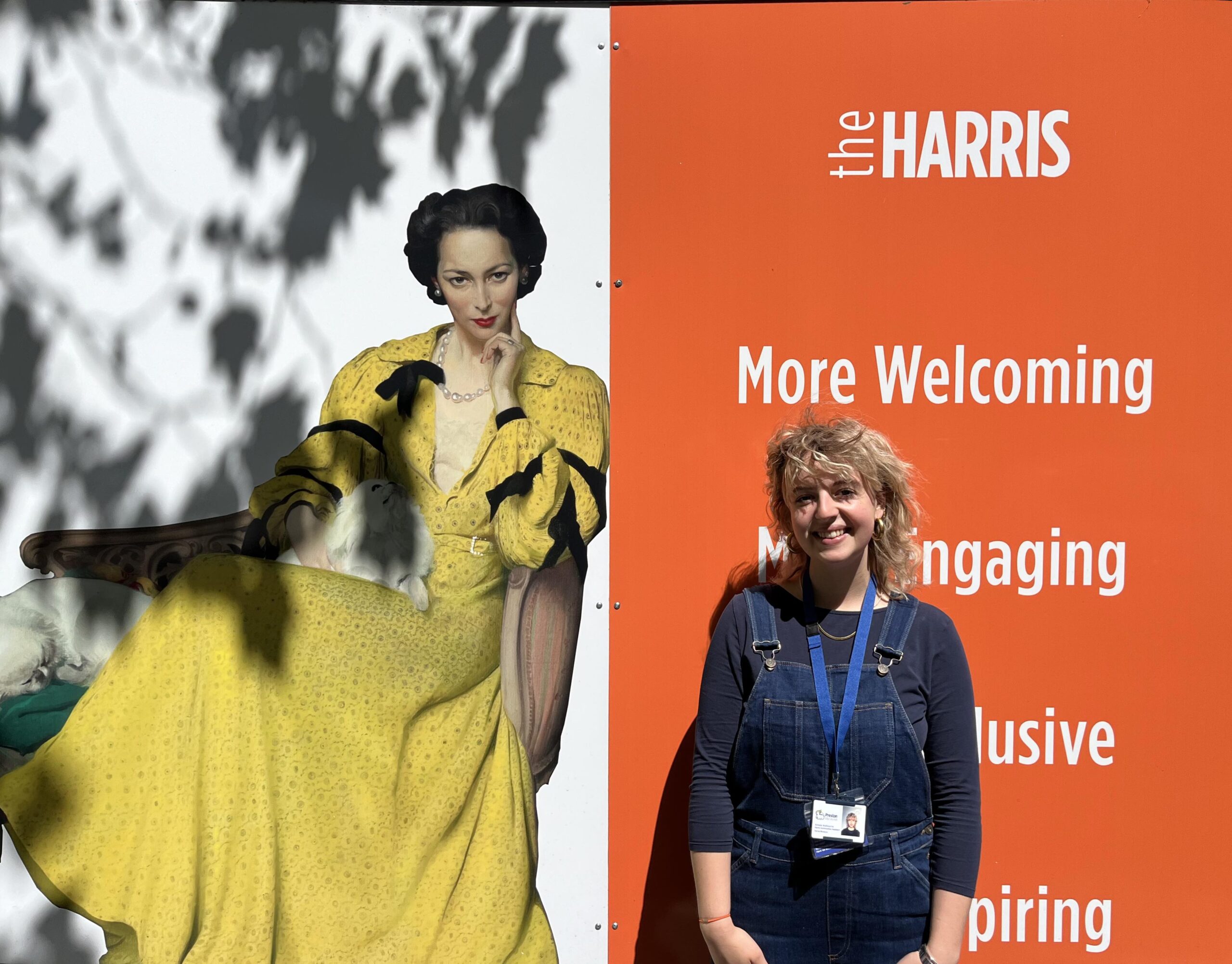 Person stands in front of a sign which says The Harris more welcoming