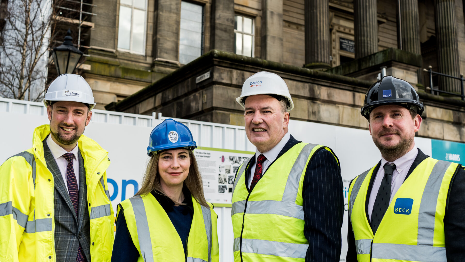 A group of people representing The Harris, Conlon and Beck stood outside the building with hard hats.