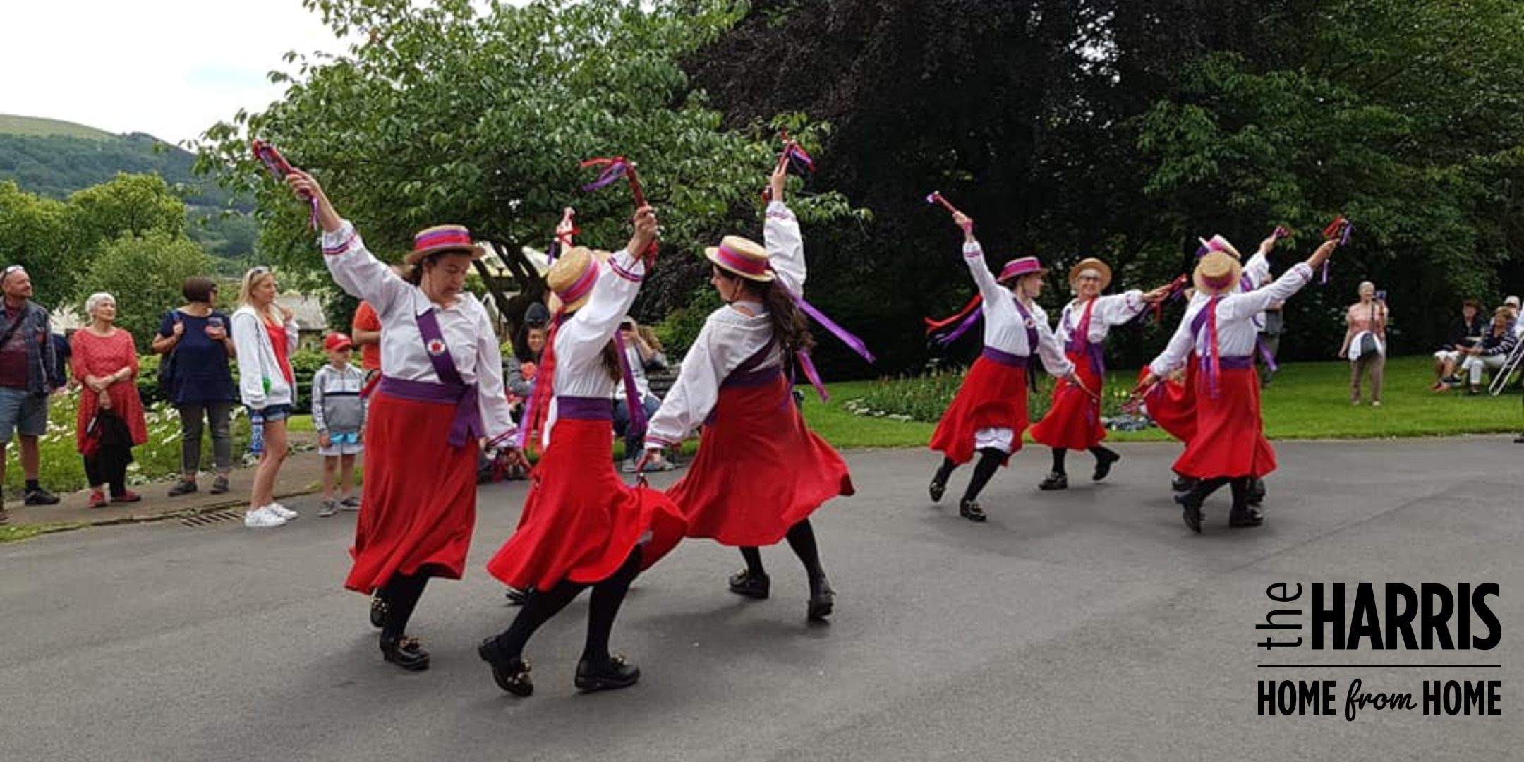 A group of people in red skirts dancing outside.