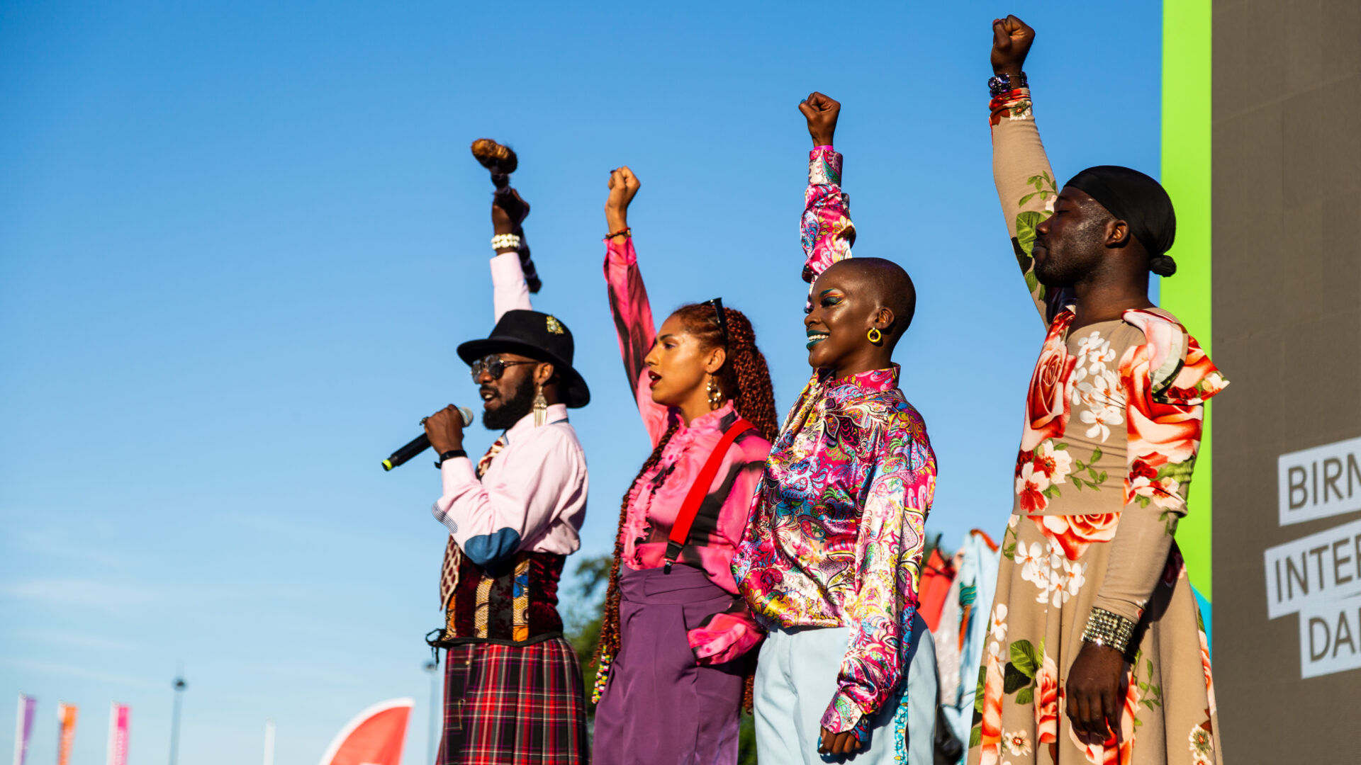 Image of four performers with their fists in the air.