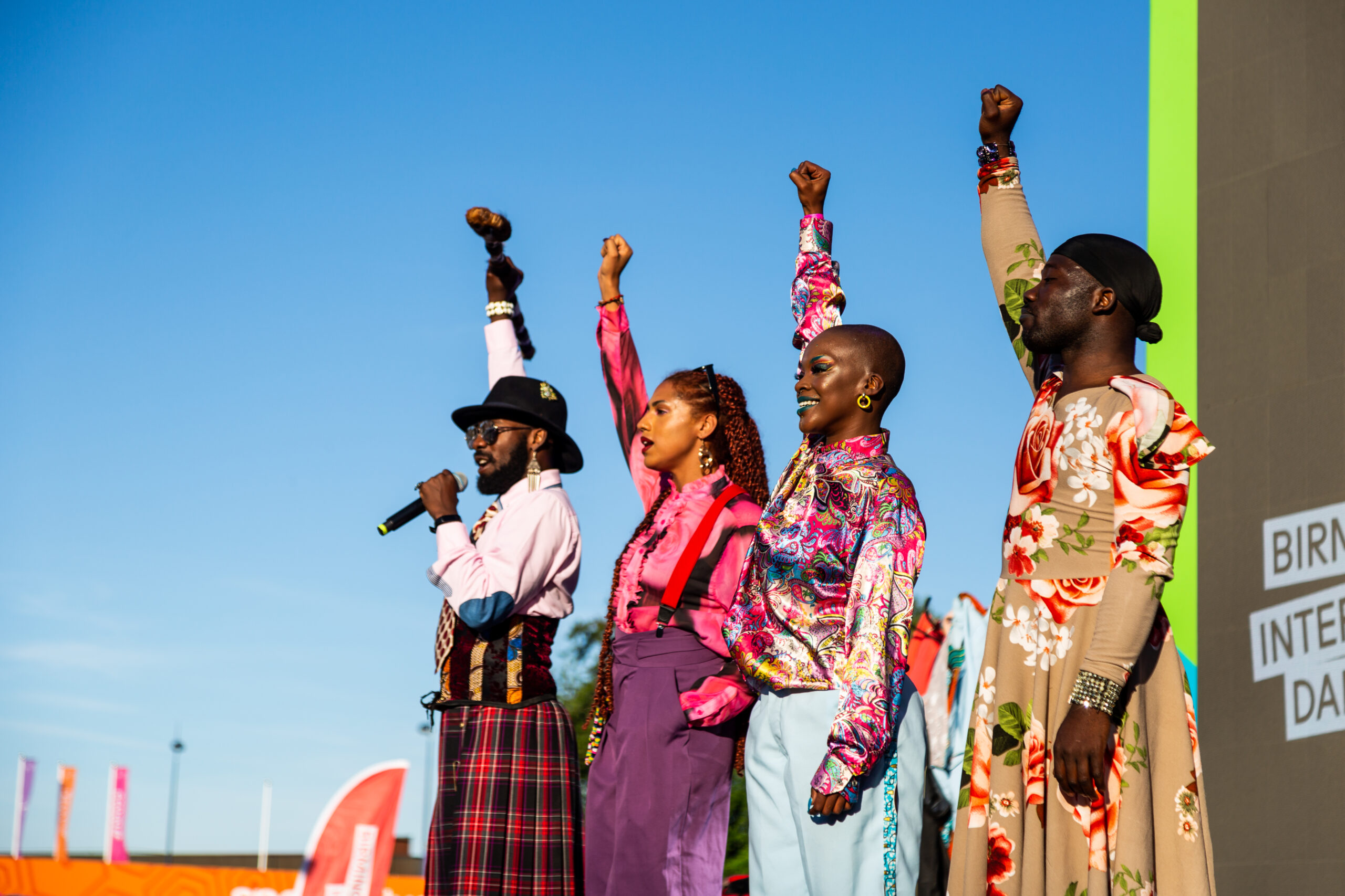 Image of four performers with their fists in the air.