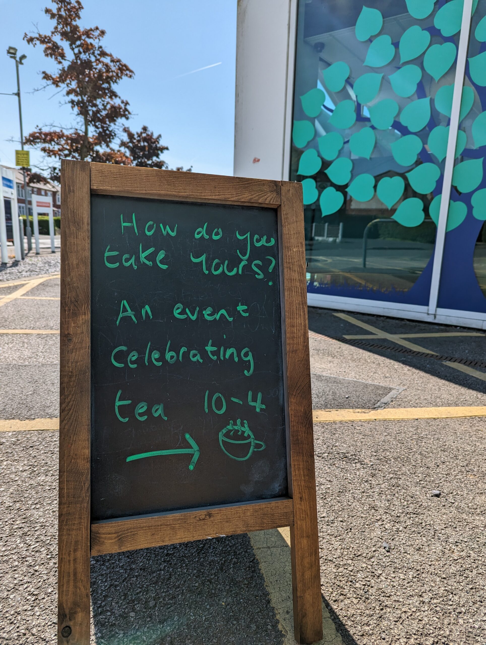 A small blackboard detailing the information about our tea event in green chalk.