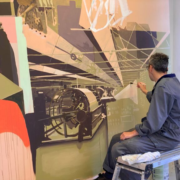 Gavin sits whilst painting a mural.