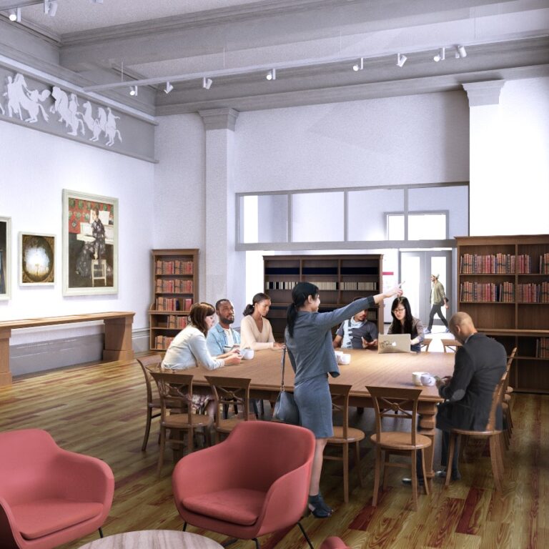 The new meeting room, featuring a table in the centre and people standing and sitting around it.