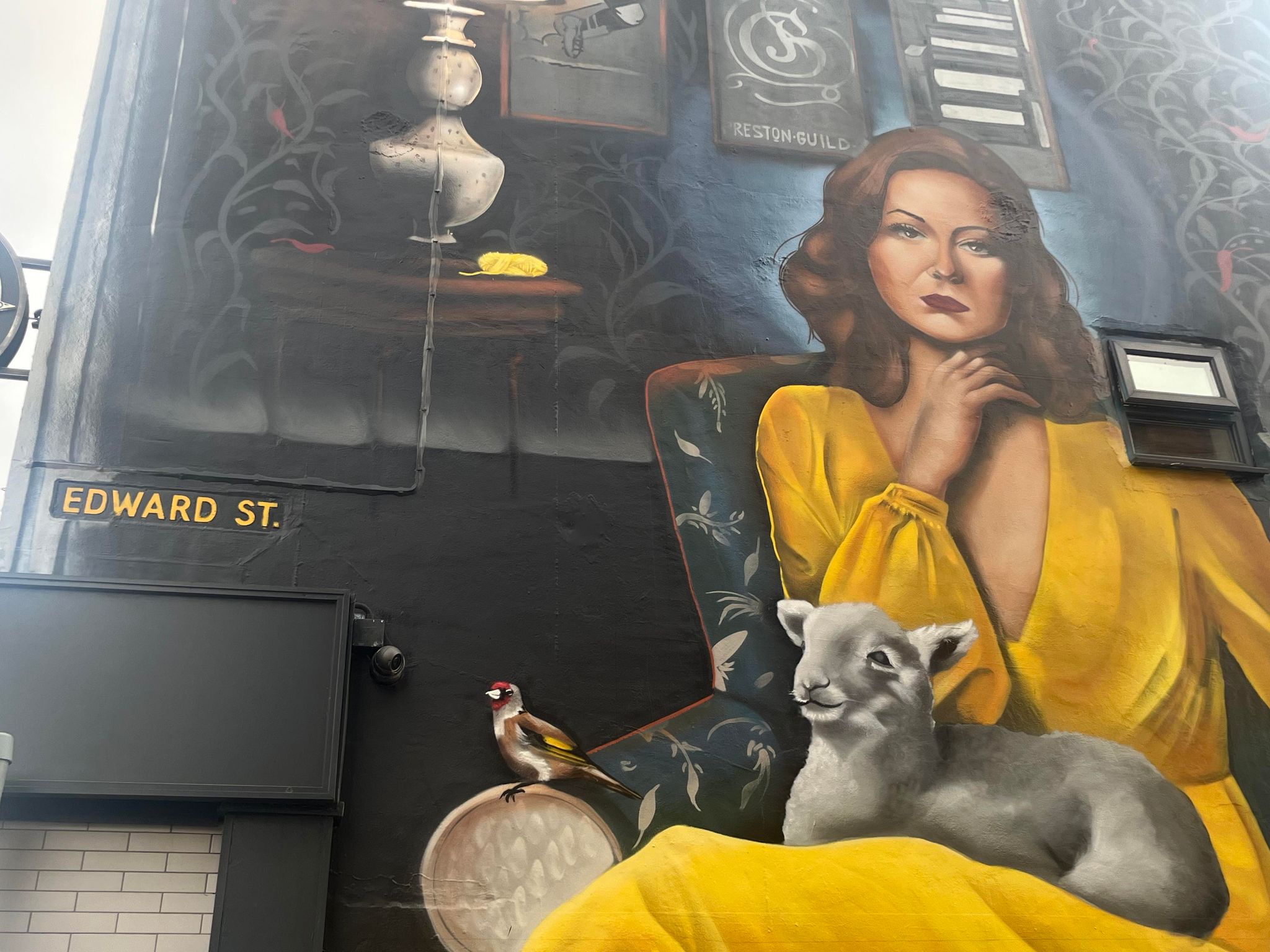 Image of a large street artwork of a woman in a yellow dress