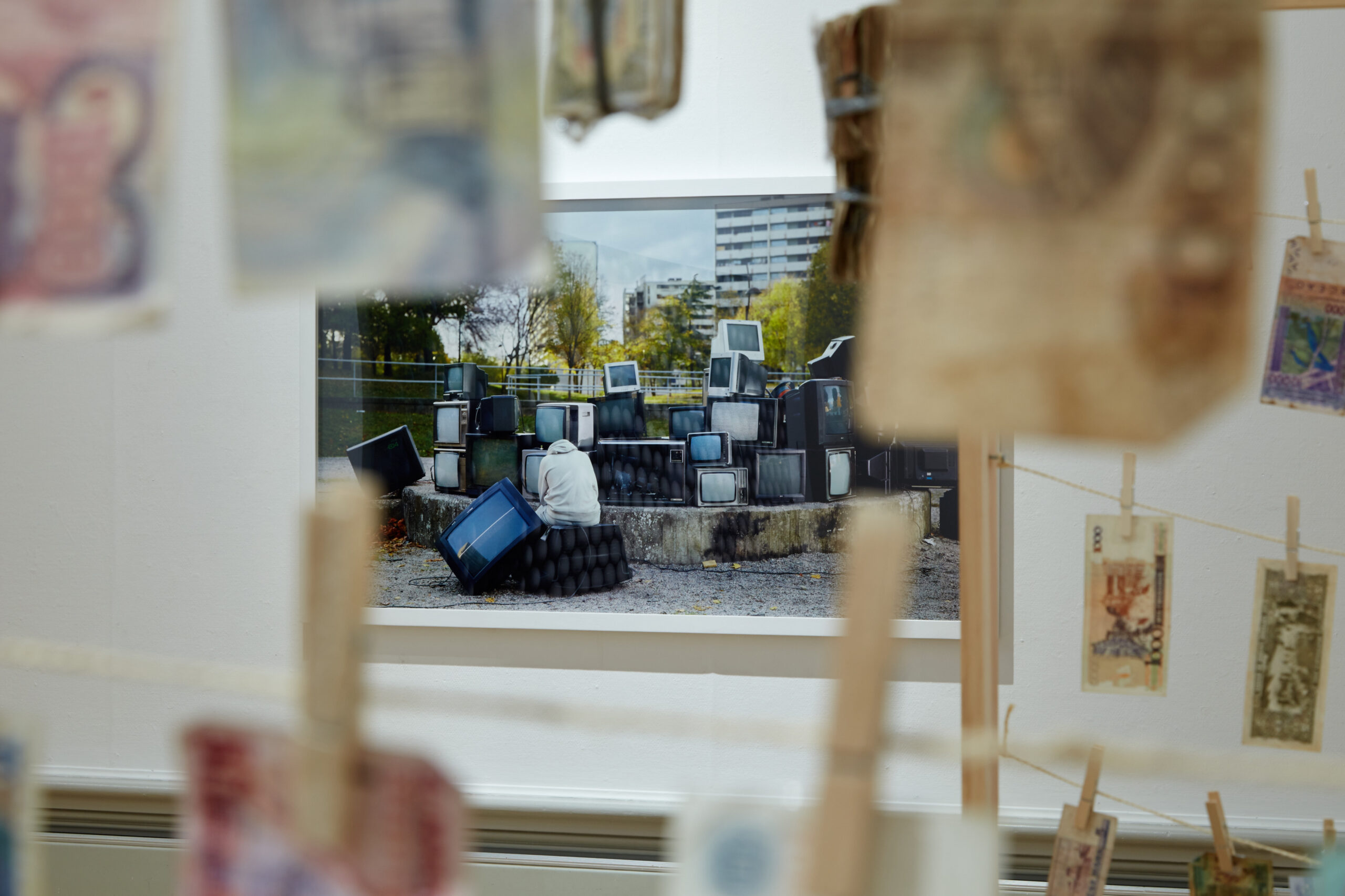 Money from around the world hangs in front of a photograph of a pile of televisions.