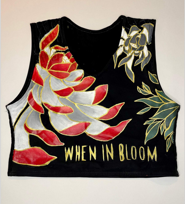 A black lyra binder painted with flowers and featuring the text 'when in bloom'.