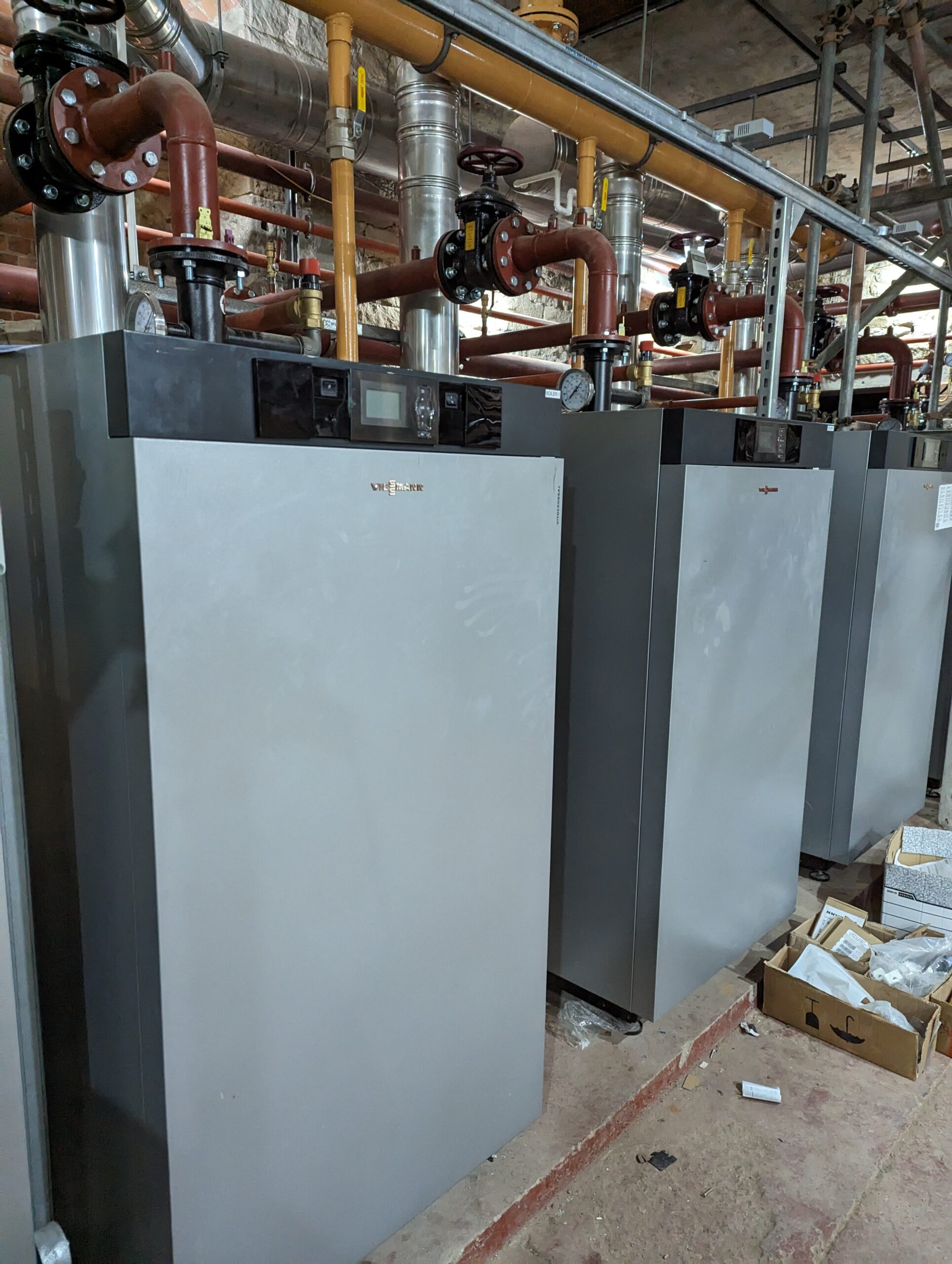 Three large grey boilers in the basement of the Harris.