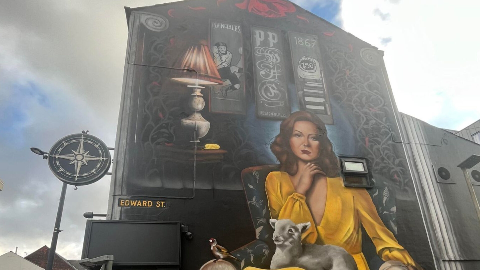 Image of a large street artwork of a woman in a yellow dress