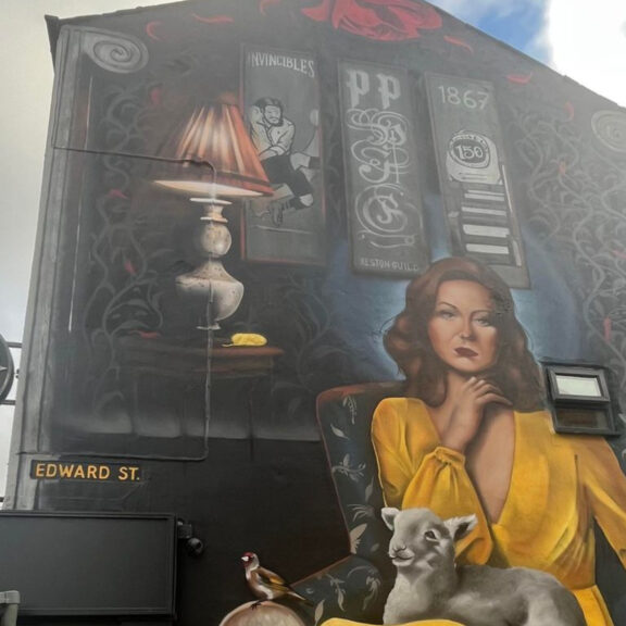 Image of a large street artwork of a woman in a yellow dress