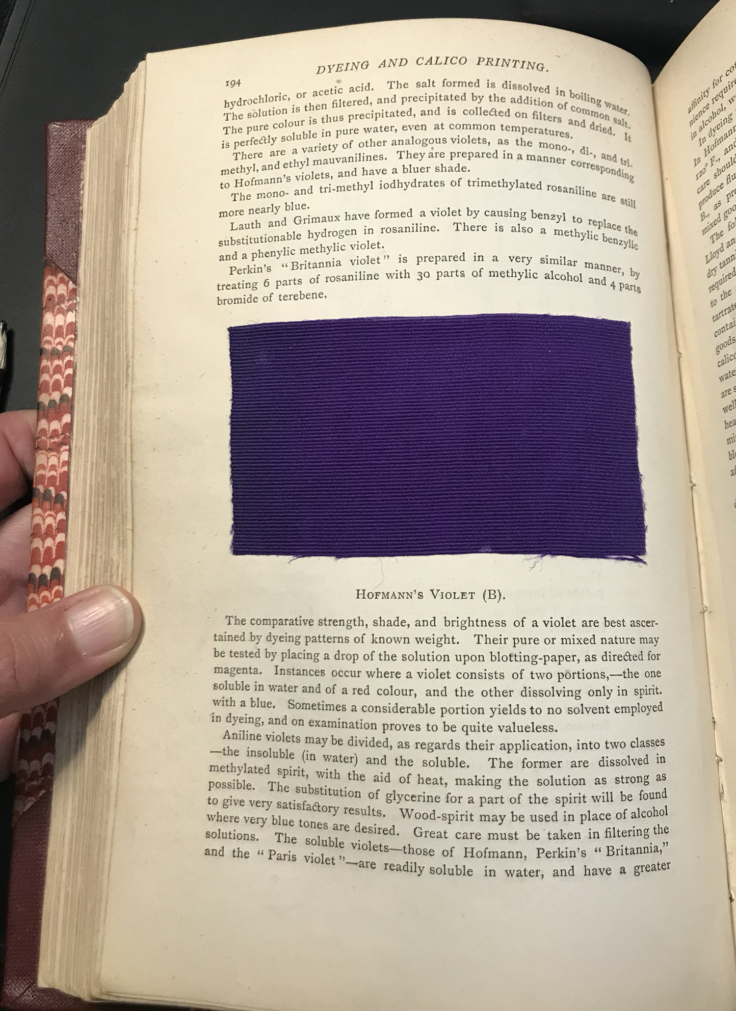 A page of a book showcasing a small piece of purple cloth.